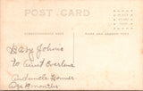 People - Child - seated in a wicker rocking chair in flannel dress RPPC - 800883