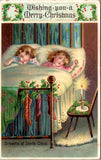 Xmas - Dreams of Santa Claus, 2 kids in bed, stockings hung on brass bed postcar