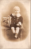 People - Child - sitting on a table holding horse and buggy toy - studio RPPC - F09067