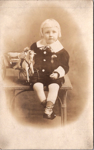 People - Child - sitting on a table holding horse and buggy toy - studio RPPC - F09067