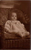 People - Child - sitting in a wicker chair, in knitted outfit - RPPC - F09148