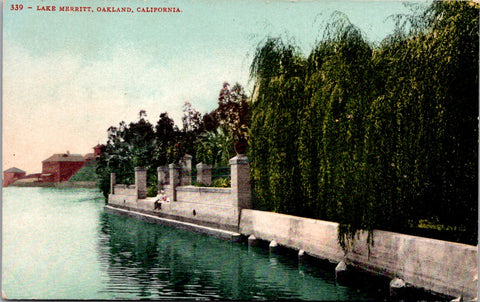 CA, OAKLAND - Lake Merritt w/bldgs, couple sitting at the ledge postcard - I0305