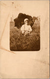 People - Child - sitting in the grass holding an open umbrella RPPC - NL0541