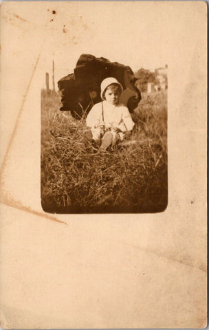 People - Child - sitting in the grass holding an open umbrella RPPC - NL0541