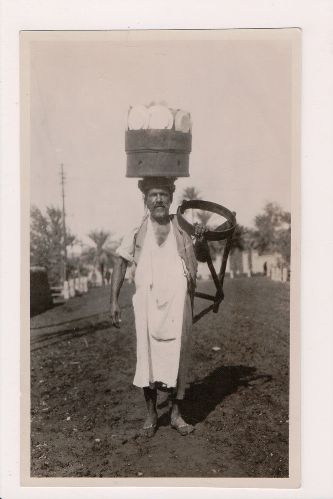 People - Native Dress - Man with container on head with plates? - NL0792